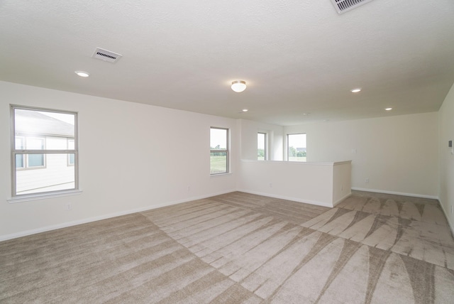 unfurnished room with recessed lighting, baseboards, light colored carpet, and visible vents