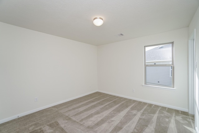 empty room featuring baseboards, visible vents, and light carpet