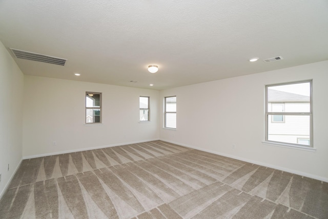 empty room with baseboards, light carpet, and visible vents