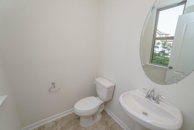 half bathroom with a sink, baseboards, and toilet