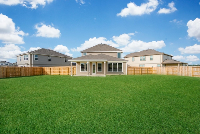 rear view of house with a fenced backyard, a patio area, and a yard
