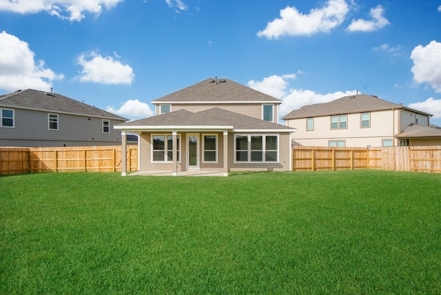 rear view of house with a lawn, a fenced backyard, and a patio area