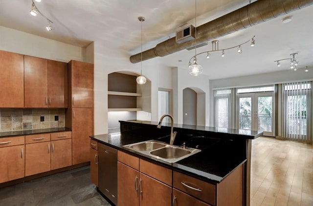 kitchen with dark countertops, a sink, dishwasher, arched walkways, and open floor plan
