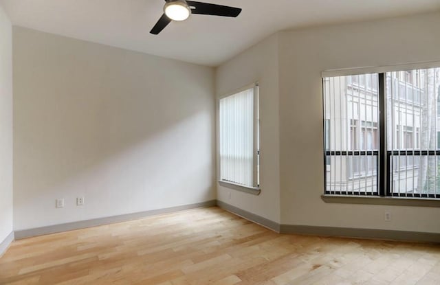 spare room with plenty of natural light, a ceiling fan, and baseboards