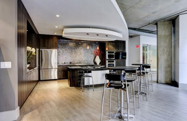 kitchen featuring appliances with stainless steel finishes, modern cabinets, dark brown cabinetry, and backsplash