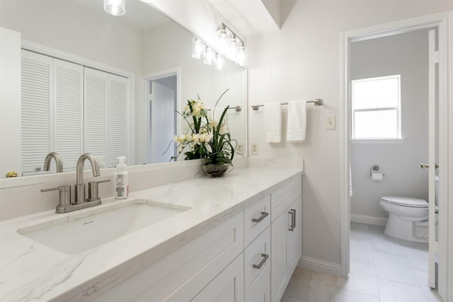 bathroom with baseboards, a closet, toilet, and vanity
