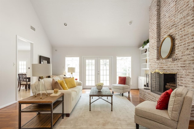 living room with visible vents, a wealth of natural light, high vaulted ceiling, and light wood-type flooring