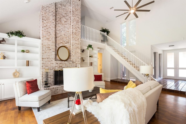 living room with stairs, a healthy amount of sunlight, and high vaulted ceiling