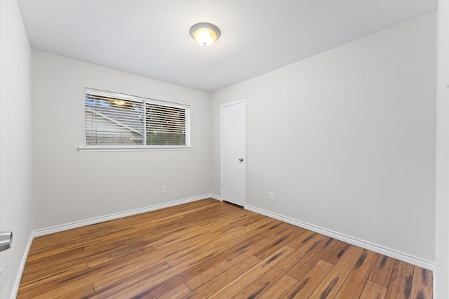 empty room with baseboards and hardwood / wood-style flooring
