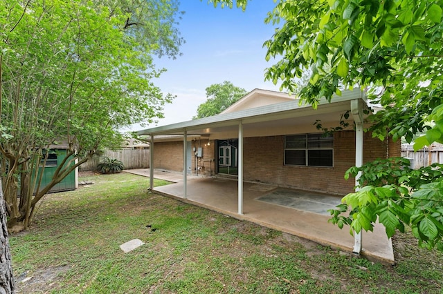 rear view of house featuring brick siding, fence, and a patio area