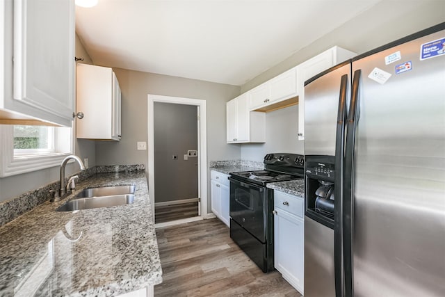 kitchen with black electric range oven, white cabinetry, stainless steel fridge with ice dispenser, a sink, and light wood finished floors
