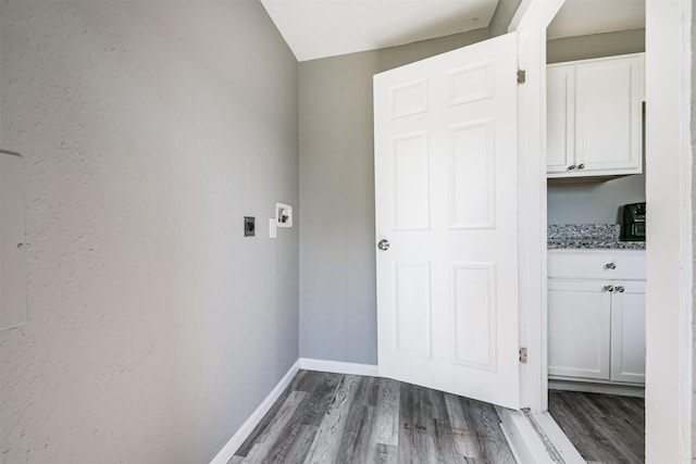 washroom with baseboards, dark wood-style flooring, electric dryer hookup, and cabinet space