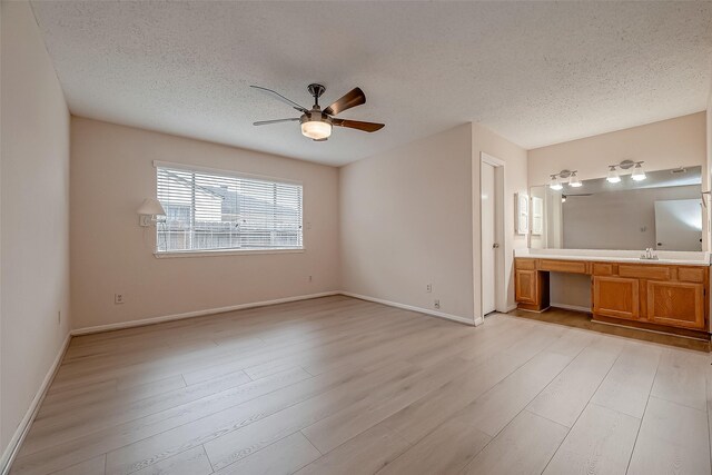 3022 Sam Houston Dr, Sugar Land, TX 77479 - unfurnished bedroom featuring a textured ceiling, light wood-style flooring, ensuite bathroom, and a ceiling fan