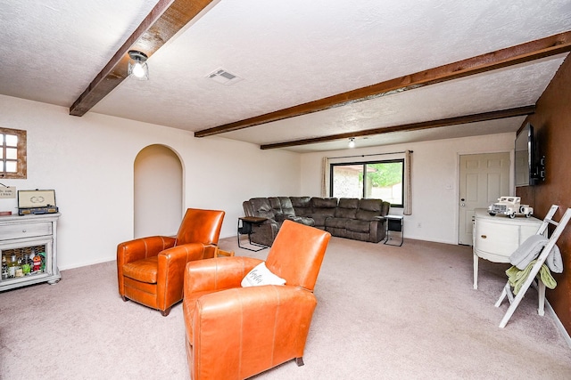 living room with visible vents, a textured ceiling, carpet, and beamed ceiling