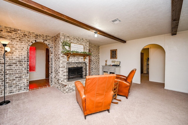 carpeted living area featuring visible vents, brick wall, a fireplace, and beamed ceiling