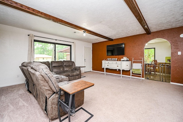 living area with light carpet, arched walkways, a textured ceiling, baseboards, and beamed ceiling