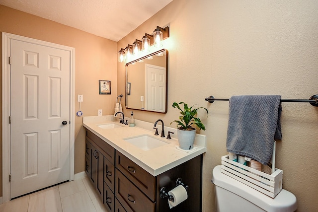 bathroom featuring a sink, tile patterned flooring, toilet, and double vanity