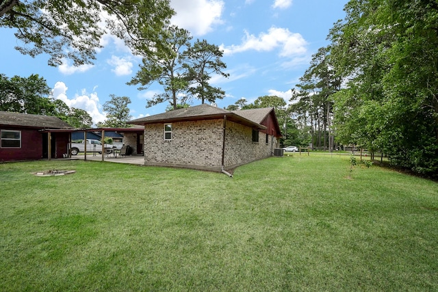 view of yard featuring fence, a fire pit, an attached carport, and a patio area