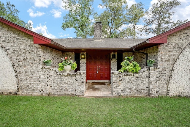 entrance to property featuring a lawn and a chimney