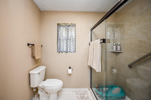 full bathroom featuring toilet, a textured ceiling, baseboards, and a stall shower