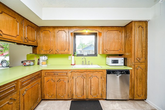 kitchen featuring white microwave, brown cabinetry, a sink, and dishwasher