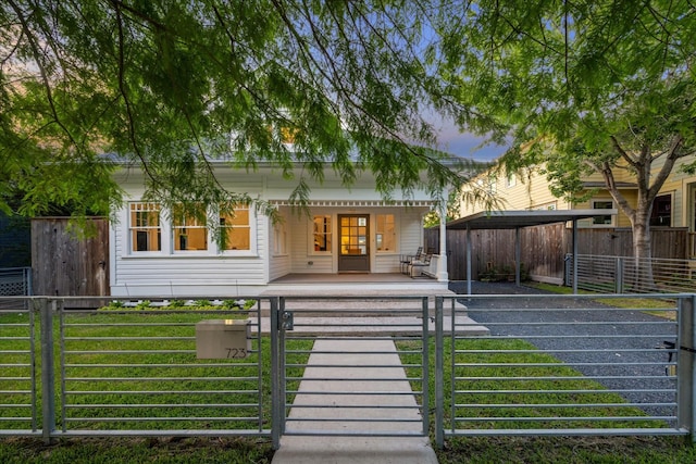 view of front of home with covered porch, a fenced front yard, a gate, and a carport