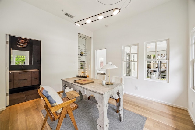 office featuring baseboards, a sink, visible vents, and light wood-style flooring