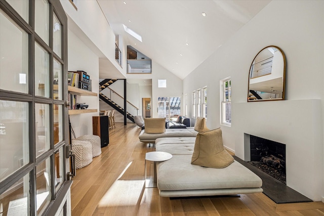 living room featuring a premium fireplace, high vaulted ceiling, and light wood finished floors