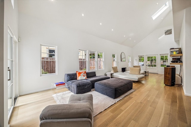 living area with recessed lighting, light wood finished floors, a skylight, and high vaulted ceiling