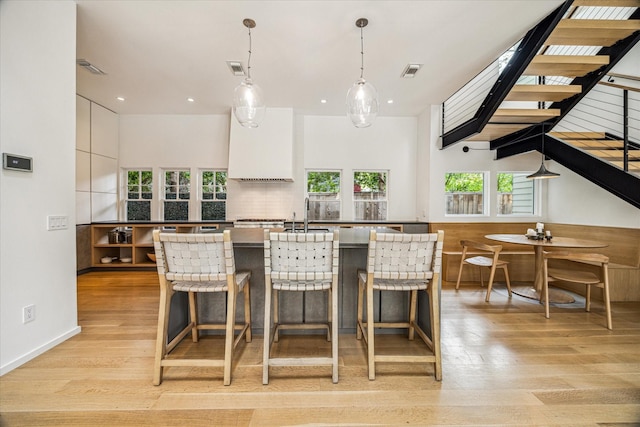 kitchen with decorative light fixtures, visible vents, light wood finished floors, recessed lighting, and an island with sink