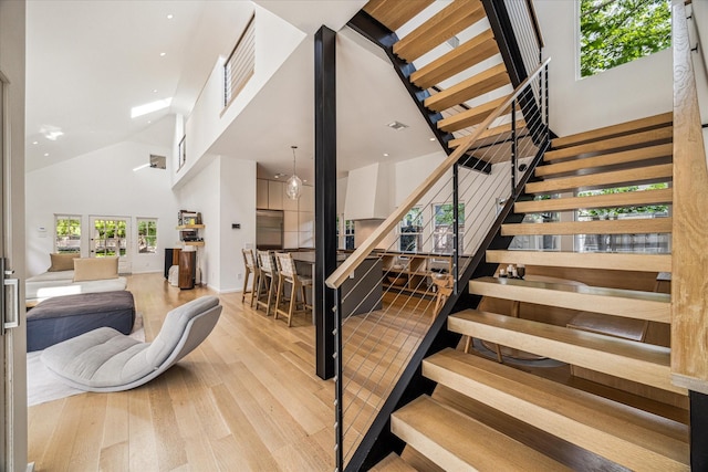 stairway featuring wood finished floors and a towering ceiling