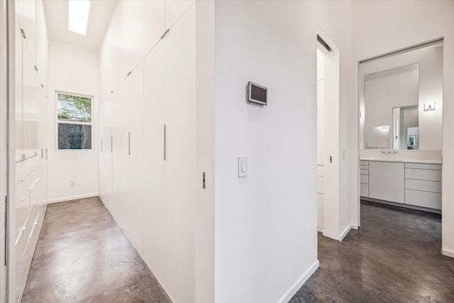 corridor with a sink, baseboards, and finished concrete floors