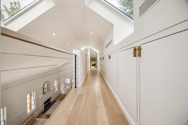 hallway featuring recessed lighting, light wood-style flooring, and lofted ceiling