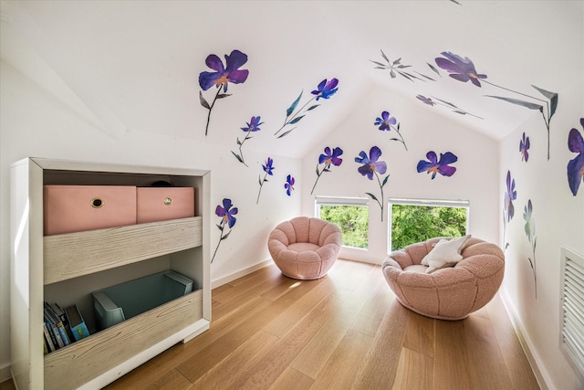 living area featuring wood finished floors, baseboards, and lofted ceiling