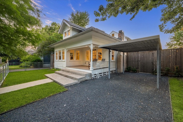 view of front of home with a detached carport, fence, covered porch, and a front yard