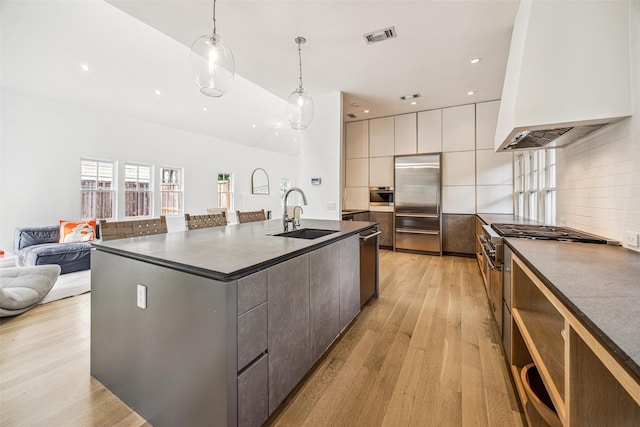 kitchen with dark countertops, high end appliances, modern cabinets, and a sink