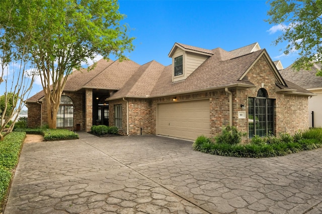 view of front of home with brick siding, an attached garage, driveway, and roof with shingles