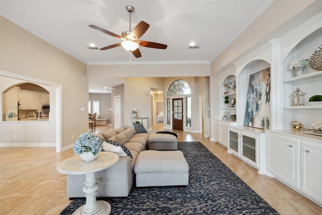 living room featuring plenty of natural light, a ceiling fan, built in features, and ornamental molding