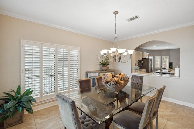 dining space featuring a notable chandelier, arched walkways, baseboards, visible vents, and ornamental molding