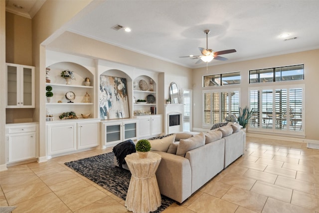 living area with a ceiling fan, ornamental molding, light tile patterned flooring, and a fireplace