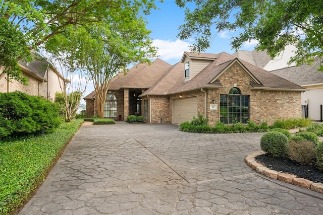 view of front of house featuring brick siding, an attached garage, driveway, and a shingled roof