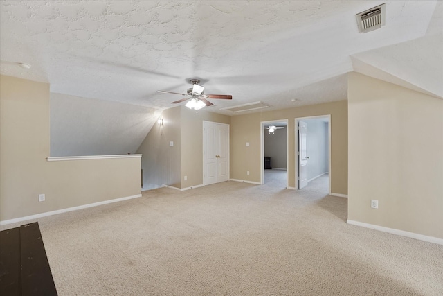 additional living space with light colored carpet, ceiling fan, visible vents, and baseboards