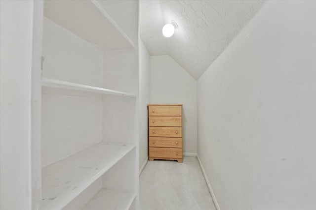 spacious closet featuring light colored carpet and vaulted ceiling