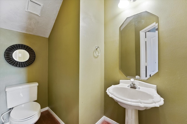 half bathroom featuring baseboards, toilet, and lofted ceiling