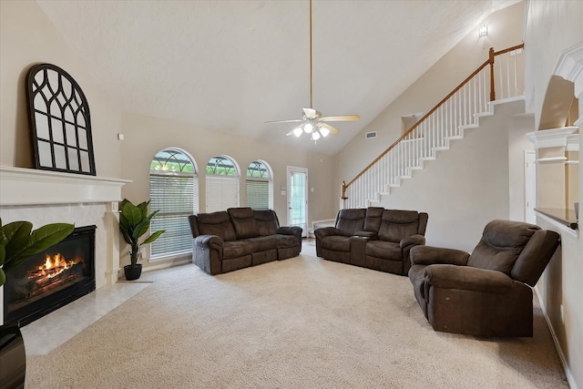 living room featuring carpet, a ceiling fan, a tile fireplace, visible vents, and stairway