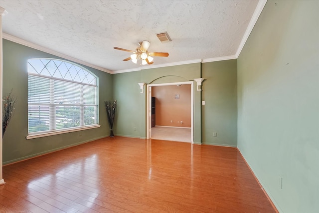 interior space featuring wood finished floors, ornamental molding, a textured ceiling, and visible vents