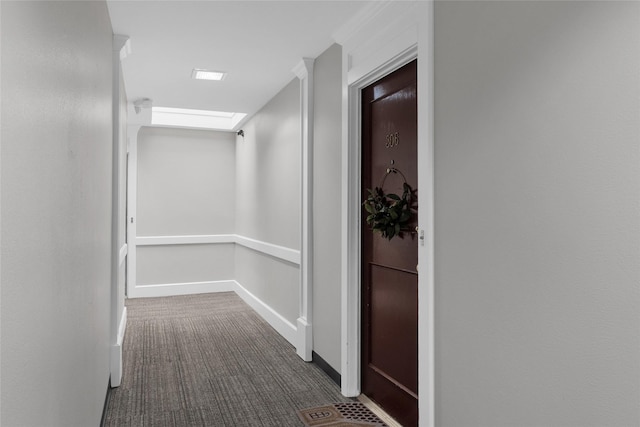 corridor with baseboards and dark colored carpet