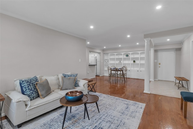 living room featuring wood finished floors, baseboards, ornate columns, ornamental molding, and recessed lighting