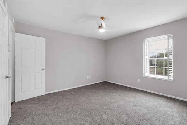 carpeted spare room featuring a ceiling fan and baseboards