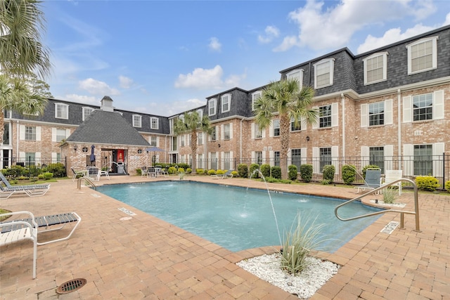 community pool with fence and a patio